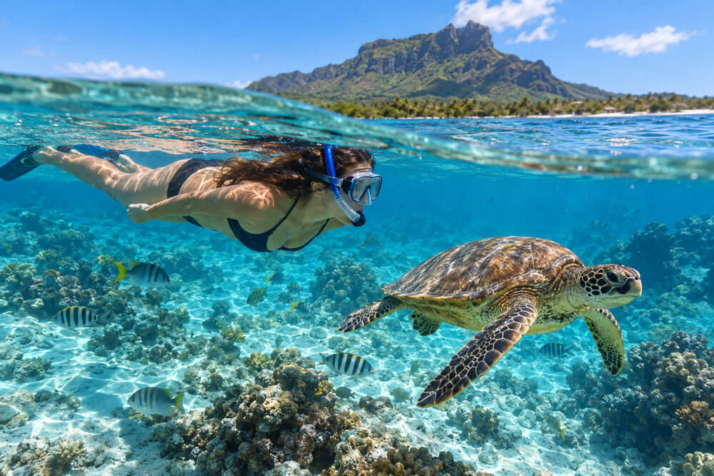 Snorkelerka ogląda żółwia morskiego ponad dnem laguny